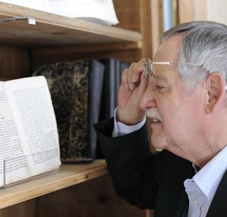 Besucher betrachtet ausgestelltes historisches Buch in der Bibliothek von Kloster Schussenried